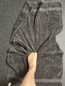 a person with foot pain gripping a towel to strengthen the quadratus plantae